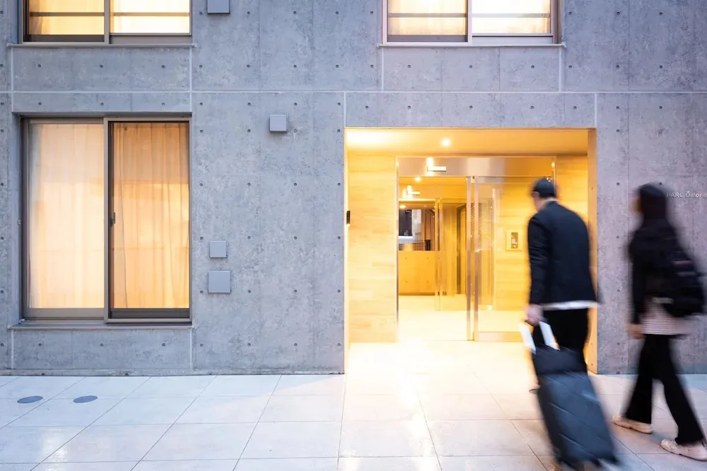 Entree d'un batiment moderne avec une personne tirant une valise.