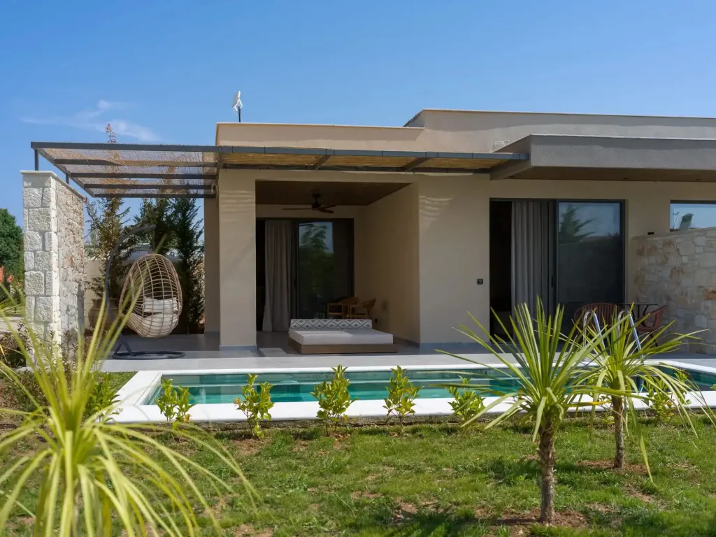 Une terrasse ombragée donne sur une petite piscine et un jardin soigné.