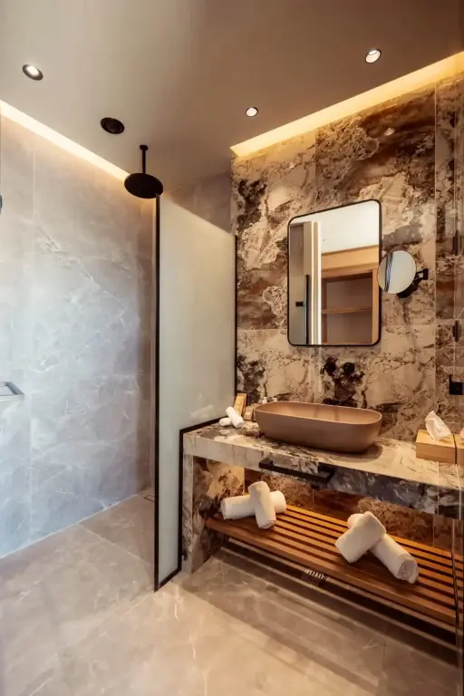 Une salle de bain moderne avec une douche à l'italienne et un lavabo sur un plan de travail en marbre.