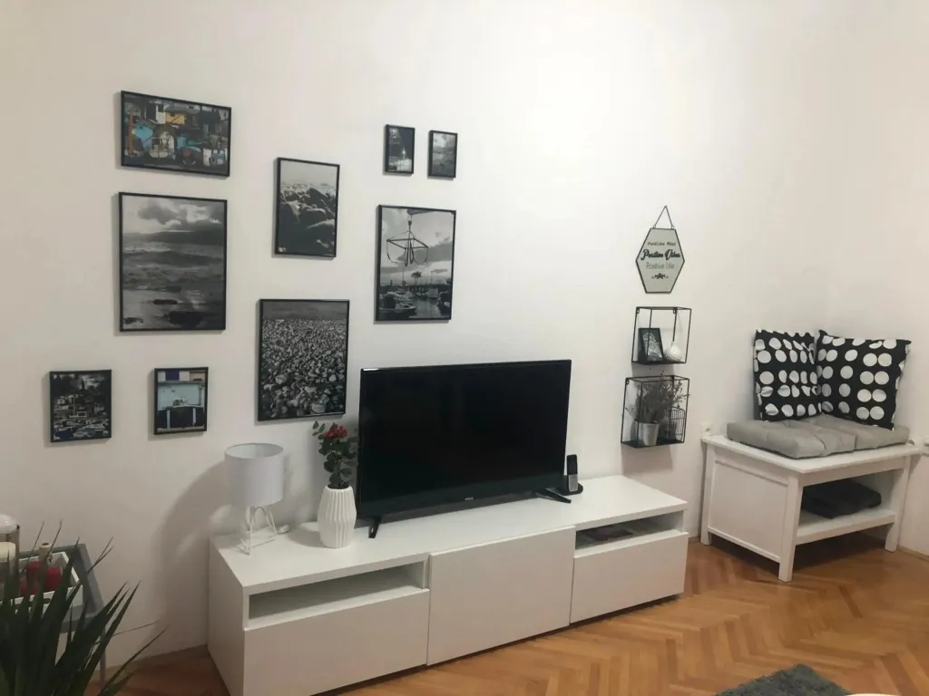 Un salon moderne avec un mur décoré de plusieurs tableaux et un meuble télé blanc.