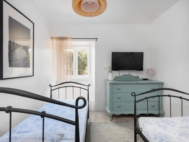 Une chambre lumineuse avec deux lits simples et une commode.