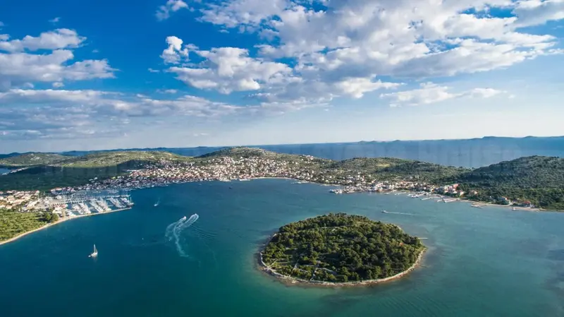 Vue aérienne d'une ville côtière avec un port de plaisance et une petite île.