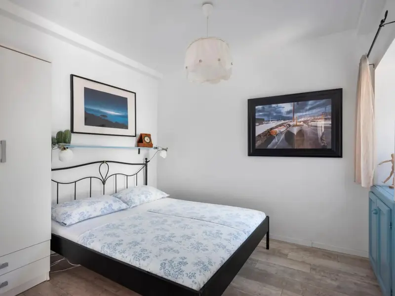 Une chambre lumineuse avec un lit double et des tableaux décoratifs.
