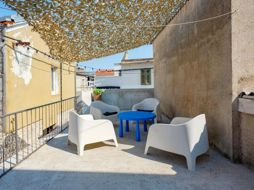 Terrasse ombragée avec mobilier de jardin en plastique.