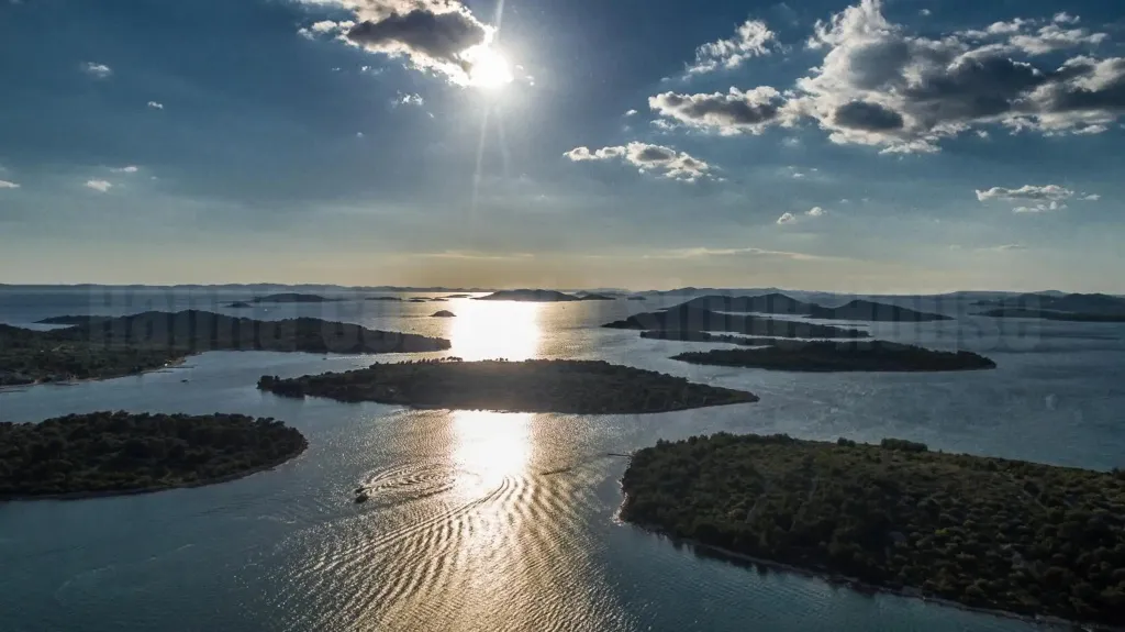 Archipel baigné de soleil avec un sillage de bateau sur l'eau.