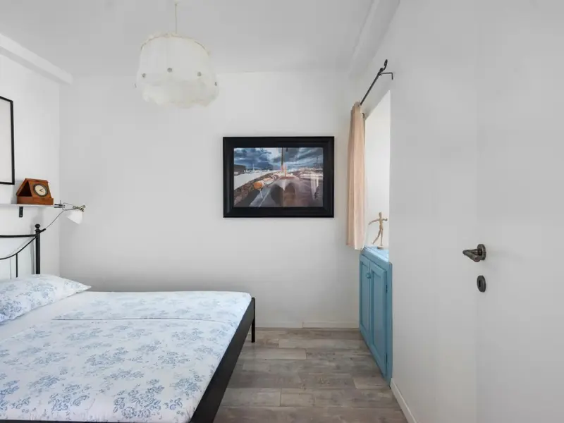 Une chambre lumineuse avec un lit recouvert d'une couette à motifs et un meuble bleu clair.