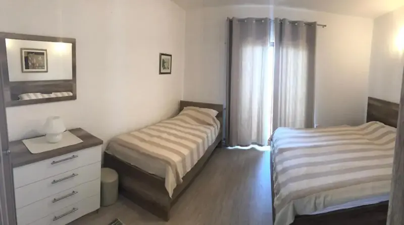 Une chambre avec deux lits simples et une commode.