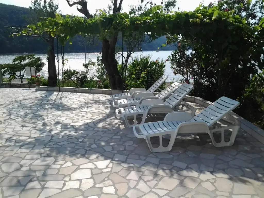 Transats blancs alignés sur une terrasse en mosaïque avec vue sur la mer.