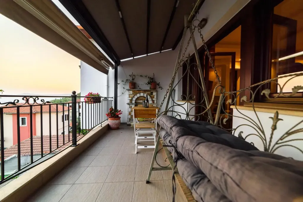 Balcon aménagé avec une balancelle et des plantes, offrant une vue sur le coucher de soleil.