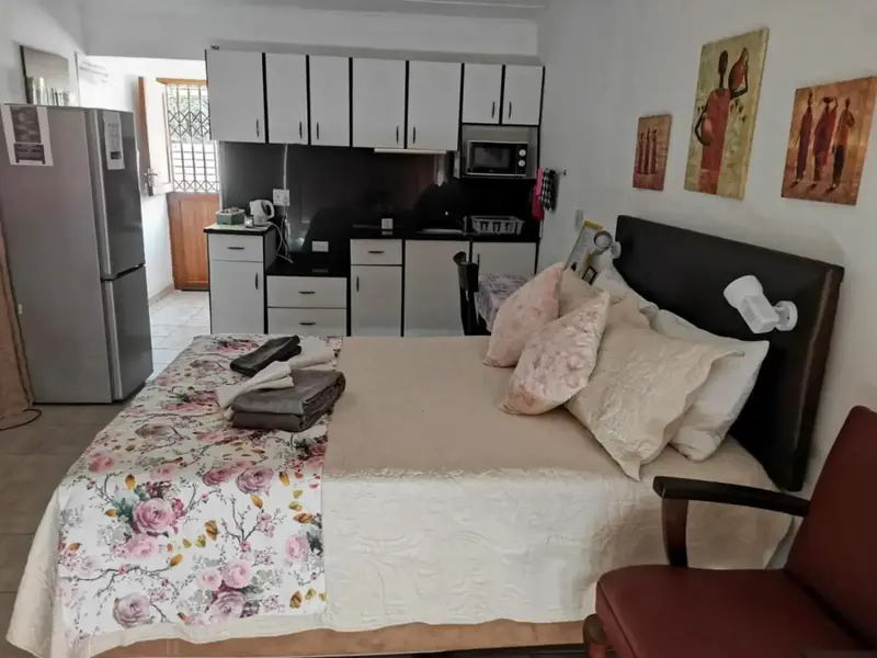 Une chambre avec un lit fait et une kitchenette équipée.