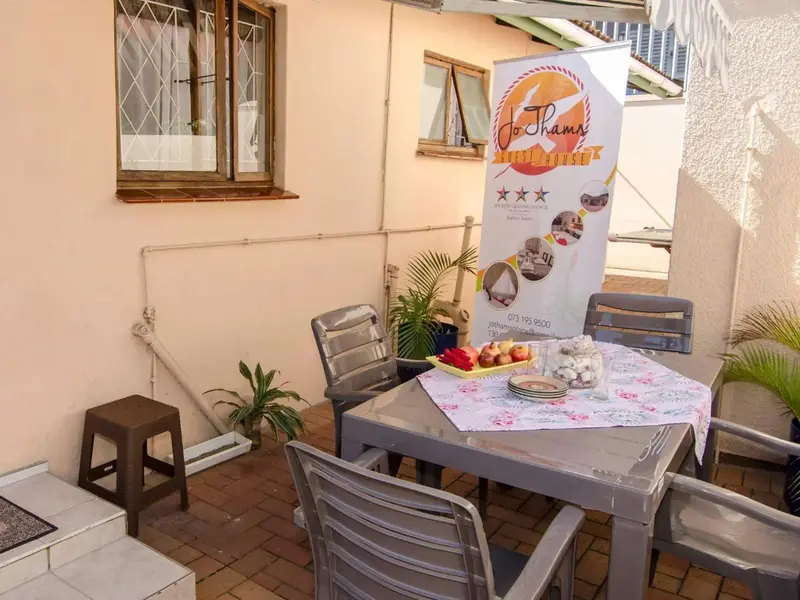 Une table et des chaises sont disposées sur une terrasse ombragée.
