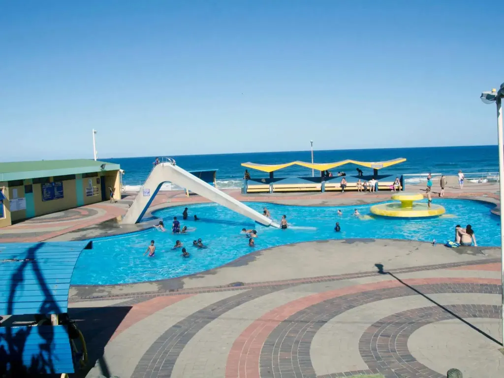 Une piscine avec un toboggan et des personnes s'amusant au bord de la mer.