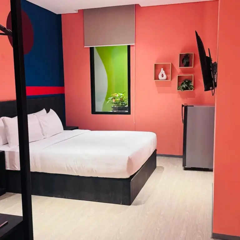 Une chambre lumineuse avec un grand lit et un mur coloré.