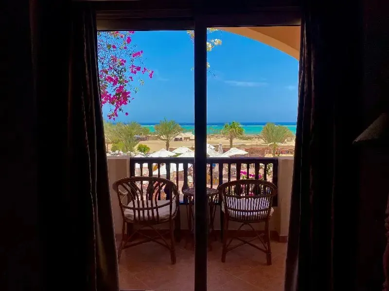Vue sur la mer depuis une terrasse ombragée avec deux fauteuils en osier.