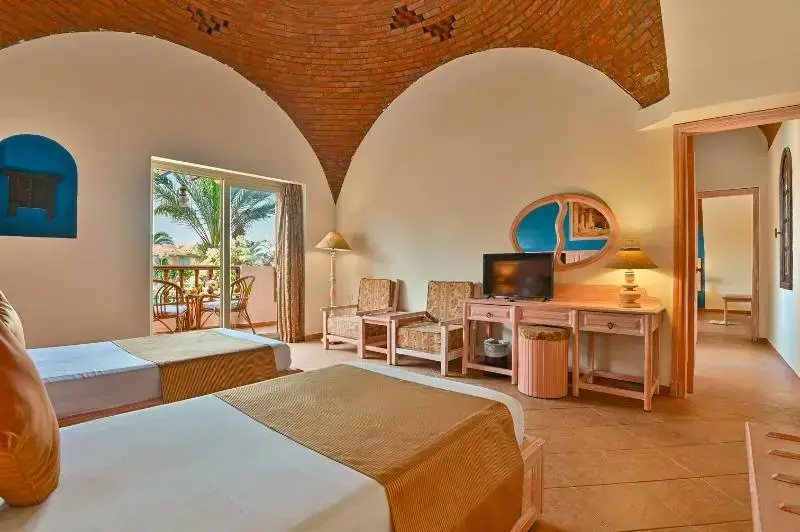 Une chambre lumineuse avec deux lits et un coin salon donnant sur une terrasse.