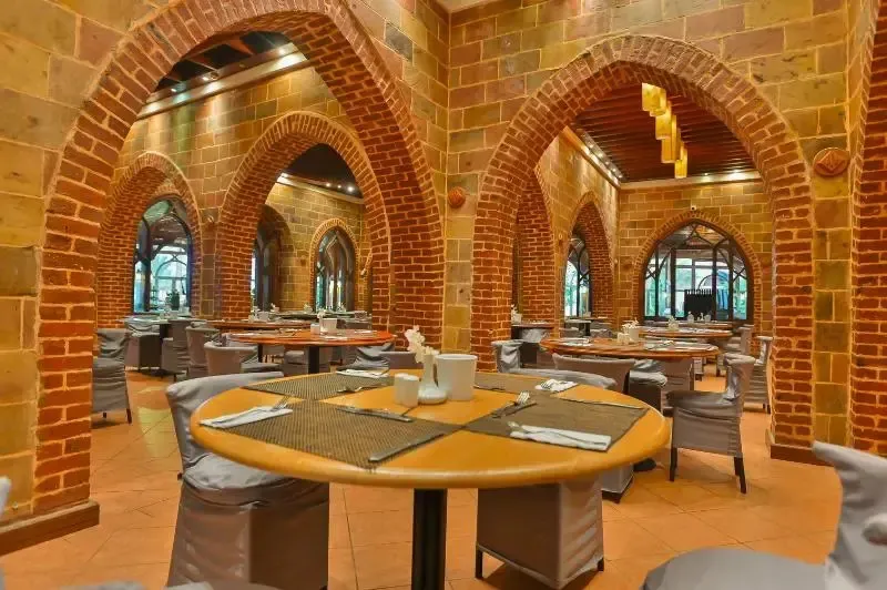 Une salle de restaurant lumineuse avec des tables dressées et des arches en briques.