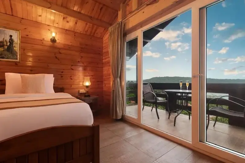 Une chambre lumineuse s'ouvre sur une terrasse avec vue sur un paysage verdoyant.
