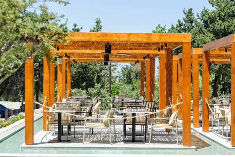 Terrasse ombragée avec tables et chaises pour les repas.