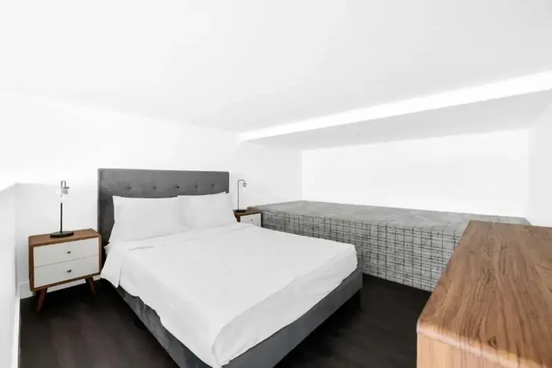 Une chambre lumineuse avec un grand lit et un espace de couchage supplémentaire.