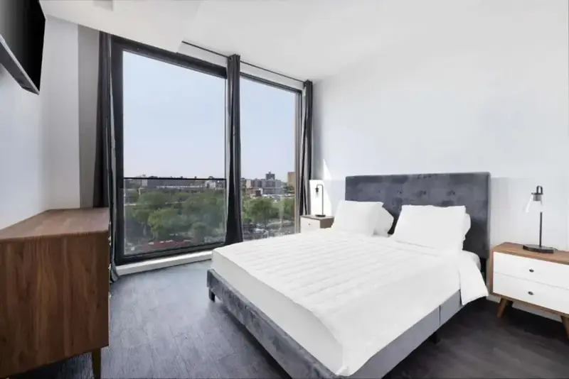 Une chambre lumineuse avec un grand lit et une vue sur la ville.