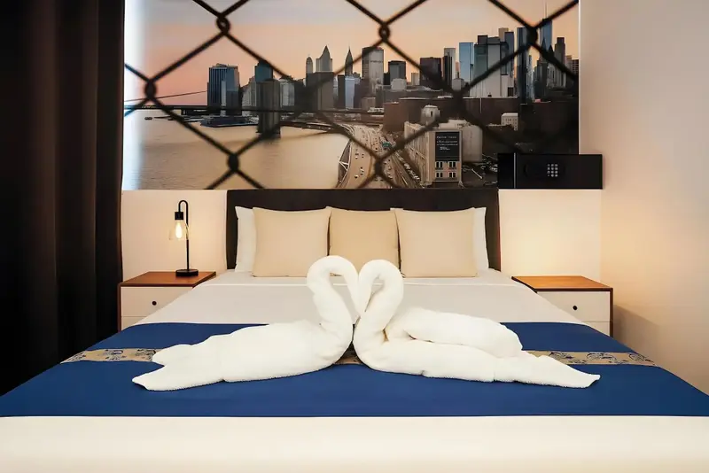Lit double soigneusement fait avec des serviettes en forme de cygnes dans une chambre d'hôtel.