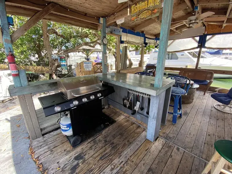 Un espace de cuisson extérieur avec un barbecue et des tabourets.