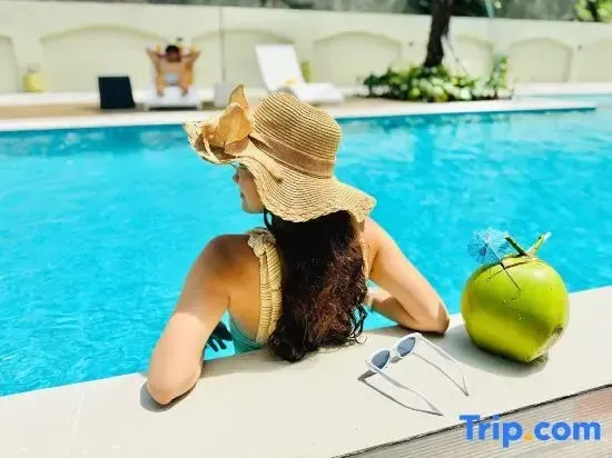 Une femme au chapeau se détend au bord d'une piscine ensoleillée.