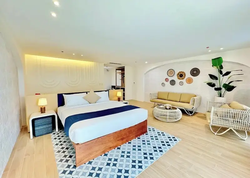 Une chambre lumineuse avec un grand lit et un espace salon.
