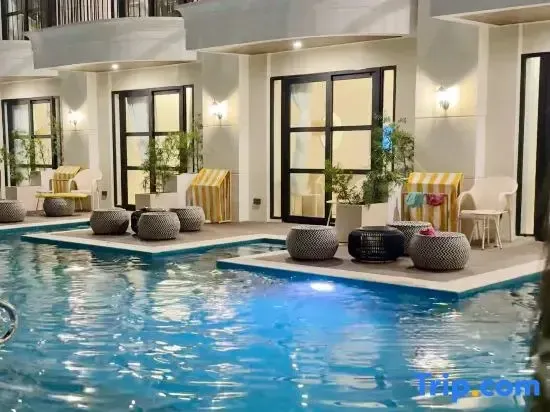 Une piscine bordée de transats et de petites tables basses.