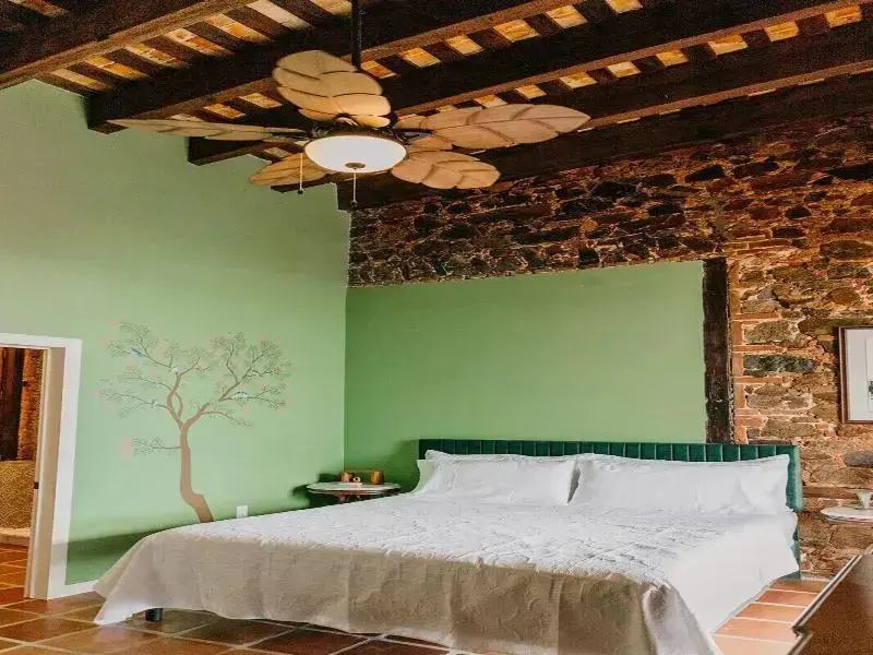 Une chambre lumineuse avec un lit recouvert d'une courtepointe blanche et un mur en pierre.