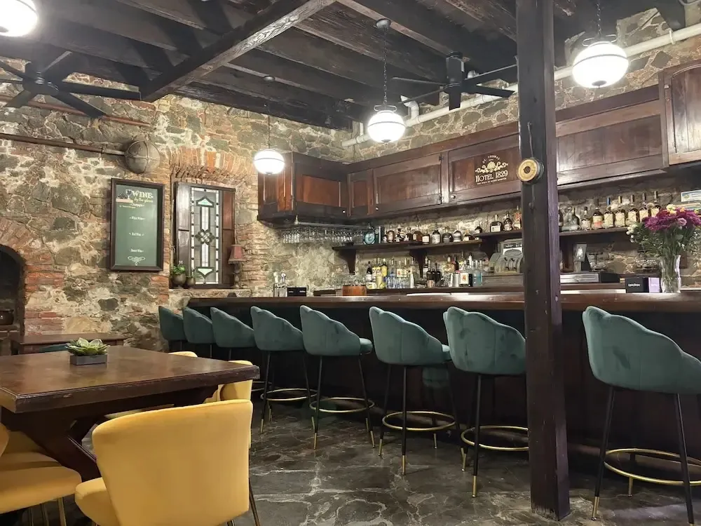 Un bar chaleureux avec un comptoir en bois et des tabourets verts.