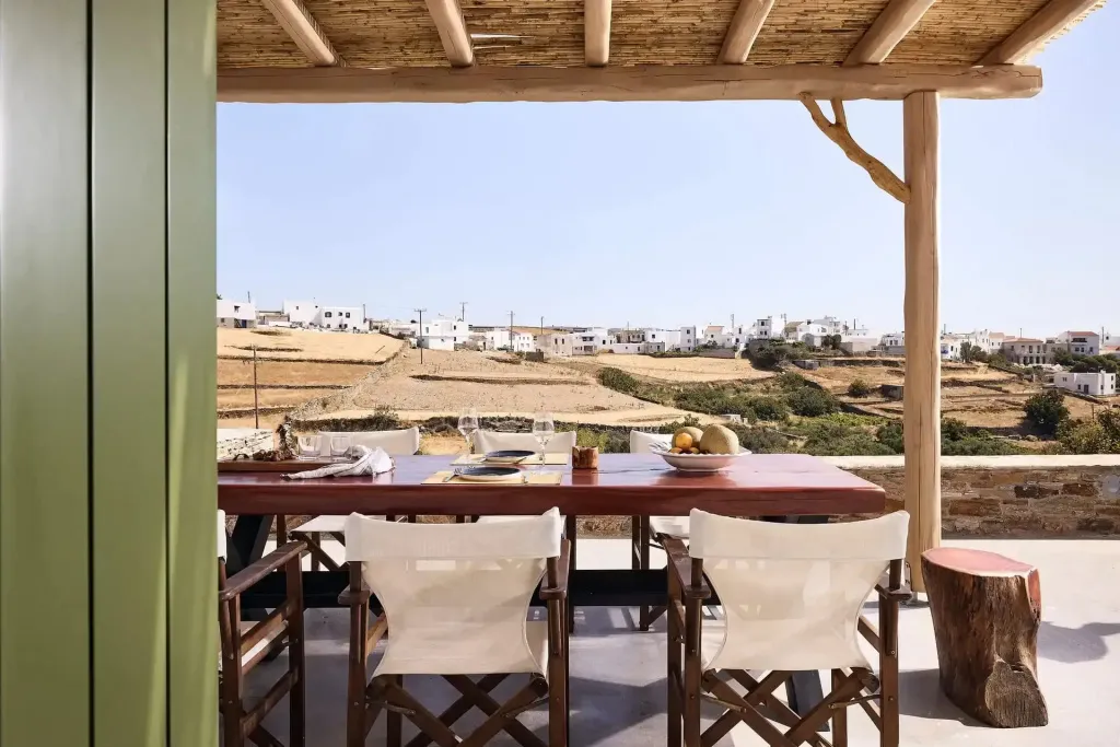 Table de repas dressée sur une terrasse ombragée avec vue sur un village.