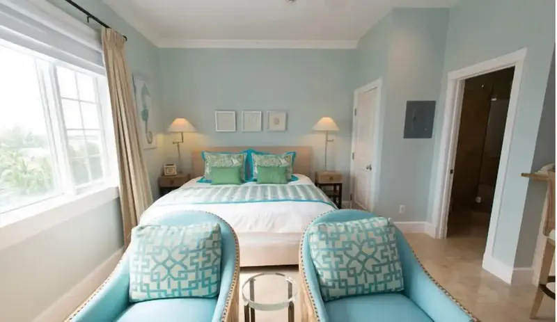 Une chambre lumineuse avec un grand lit et deux fauteuils.