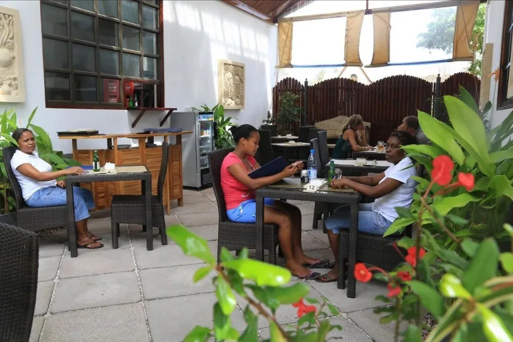 Des clients sont assis à des tables dans un espace extérieur couvert.