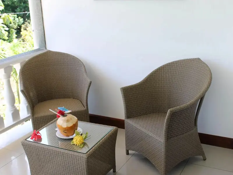 Deux fauteuils en rotin disposés autour d'une petite table basse sur une terrasse.
