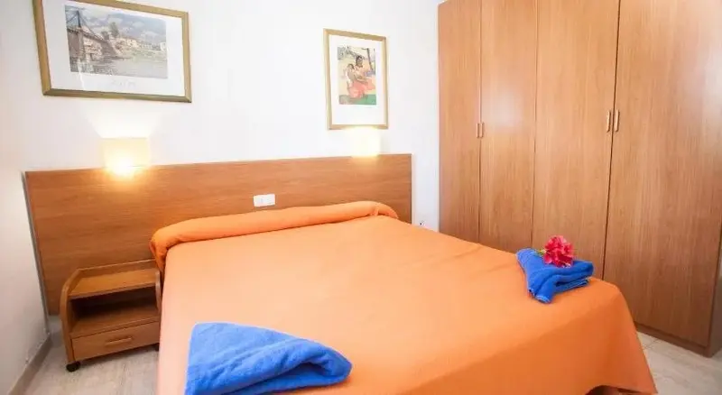 Une chambre lumineuse avec un grand lit recouvert d'une couverture orange et de coussins.