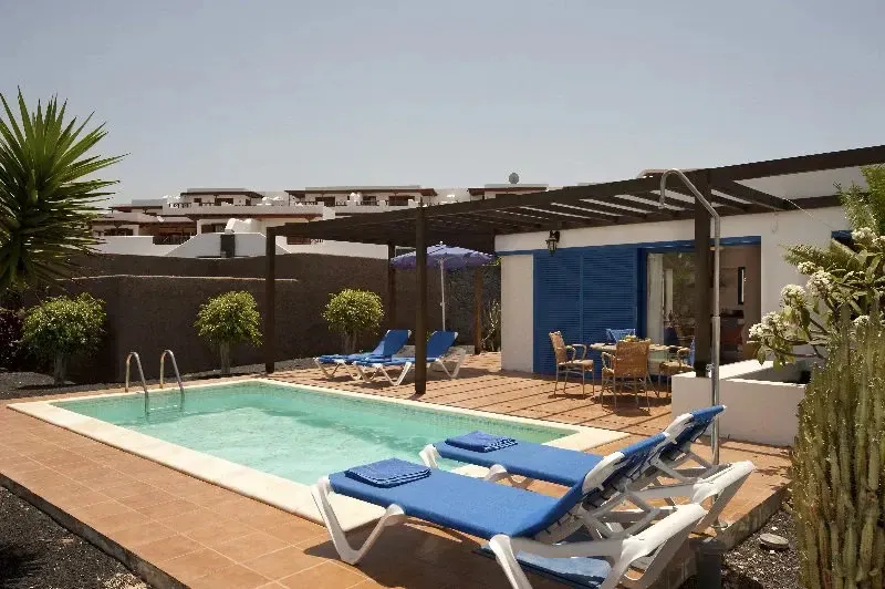 Une piscine rectangulaire avec des transats bleus sous un auvent.