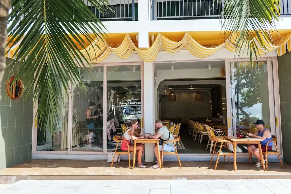 Clients assis à des tables devant la façade d'un établissement.