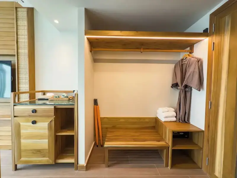 Espace de rangement avec étagères et penderie en bois clair.