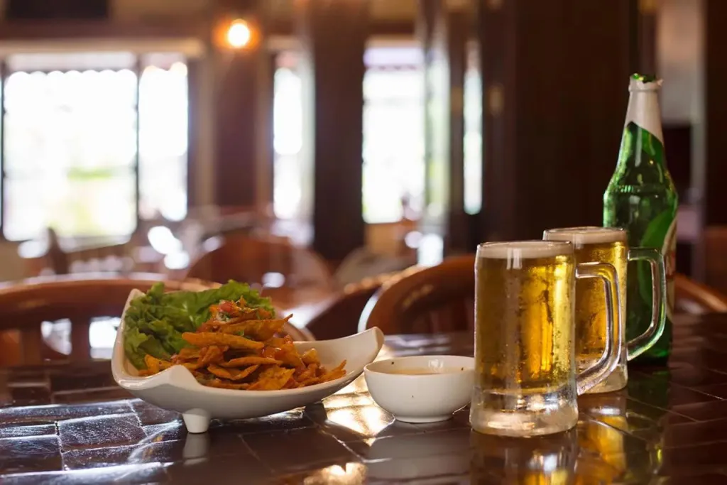 Assiette de frites et deux choppes de bière sur une table en bois.