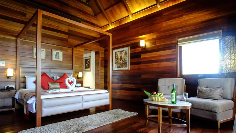 Une chambre lumineuse avec un grand lit à baldaquin et un coin salon.