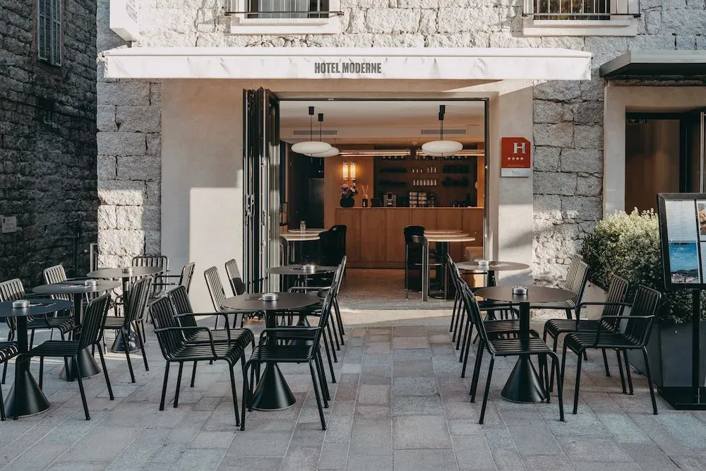 Terrasse d'hôtel avec tables et chaises devant l'entrée.