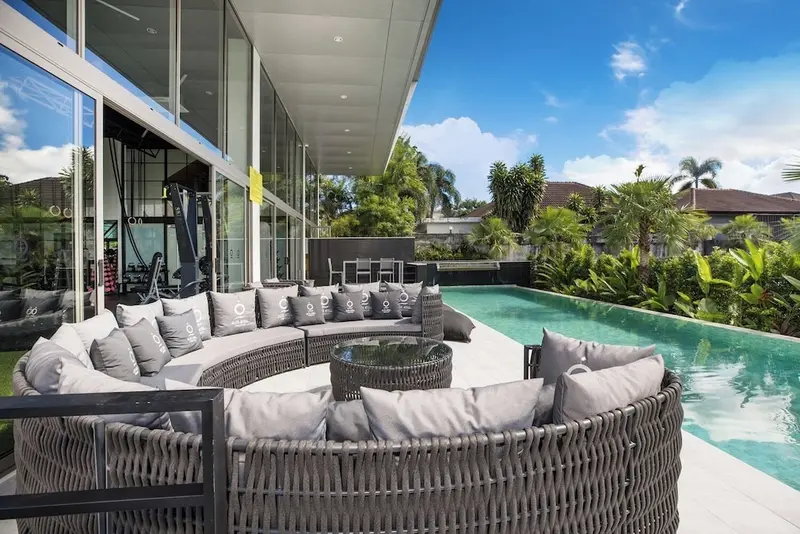 Salon d'extérieur avec mobilier en rotin et piscine turquoise.