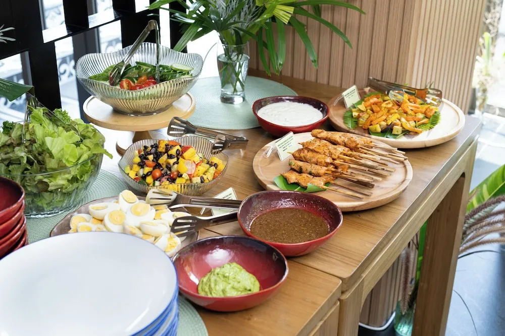 Un buffet propose une variété de salades, de fruits et de brochettes.