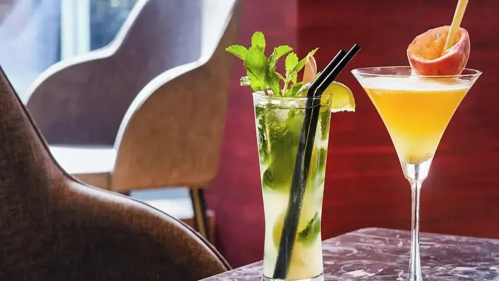Deux cocktails colorés sont présentés sur une table marbrée.