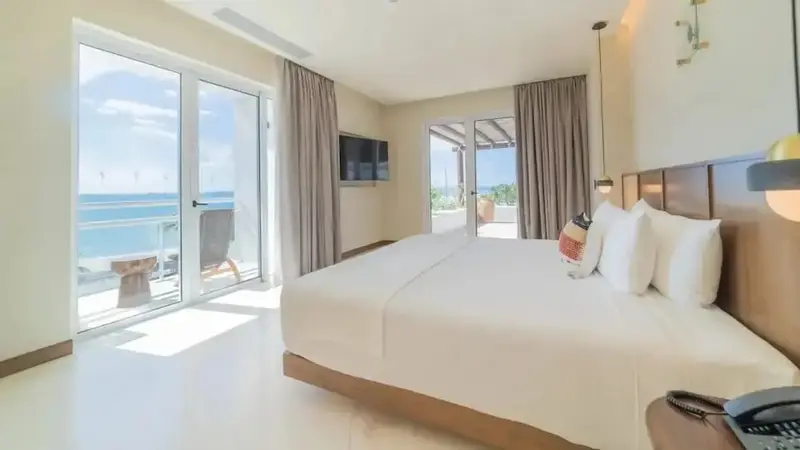 Une chambre lumineuse avec un grand lit donnant sur une vue mer.