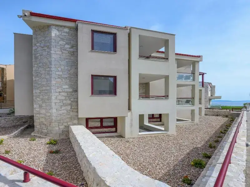 Façade d'un bâtiment moderne avec des balcons et un jardin soigné.