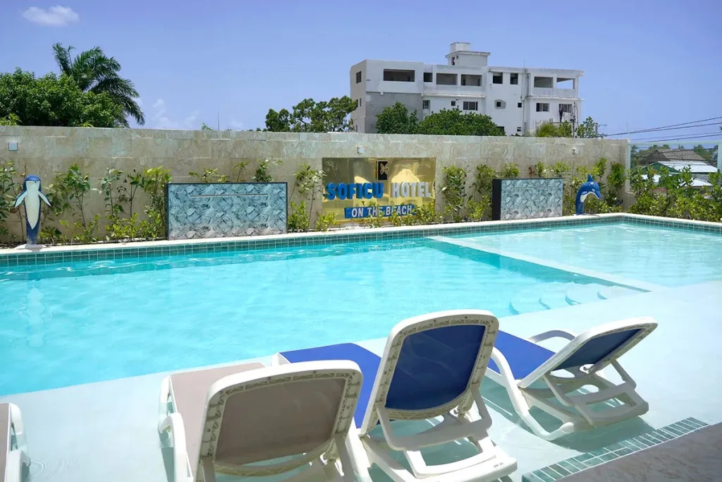 Transats bleus au bord d'une piscine turquoise avec un bâtiment blanc en arrière-plan.