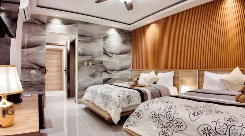 Deux lits jumeaux dans une chambre décorée de bois et de motifs graphiques.