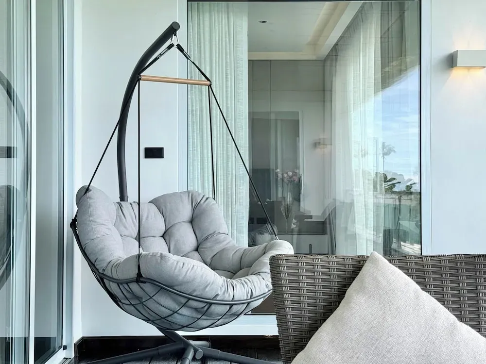 Un fauteuil suspendu se trouve sur une terrasse avec vue sur l'extérieur.